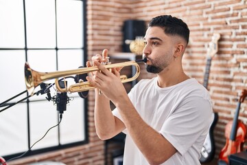 Young arab man musician playing trumpet at music studio - obrazy, fototapety, plakaty