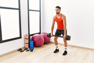 Young arab man training with dumbbells at sport center