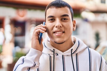 Young man smiling confident talking on the smartphone at street