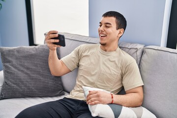 Young man watching video sitting on sofa at home