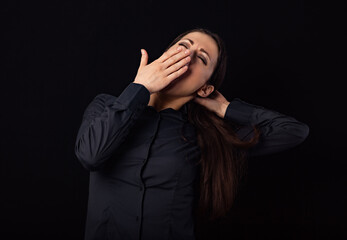 Beautiful business tired woman want to sleep and yawning in blue shirt isolated on black background with empty copy space. Closeup