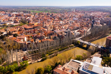Drone view of Aranda de Duero cityscape on river banks in spring overlooking terracotta tiled roofs...