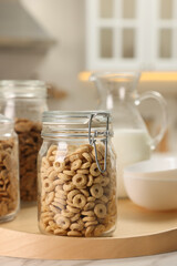 Glass containers with different breakfast cereals on white marble table in kitchen