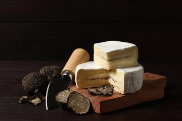 Delicious cheese, fresh black truffles and knife on wooden table