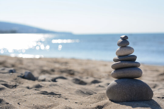 Stack of stones on sandy beach, space for text