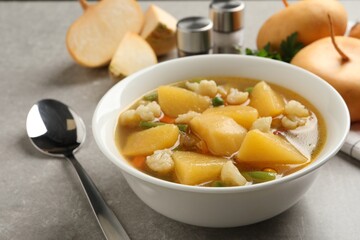 Bowl of delicious turnip soup served on light grey table