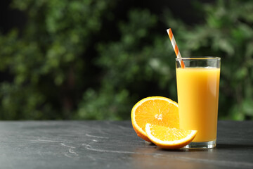 Glass of orange juice and fresh fruits on grey table. Space for text