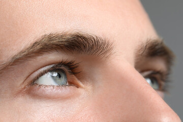 Closeup view of young man with beautiful eyes on grey background