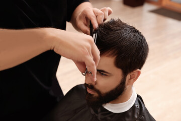 Fototapeta premium Professional hairdresser working with client in barbershop, closeup
