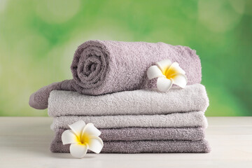 Obraz na płótnie Canvas Soft folded towels and plumeria flowers on white wooden table