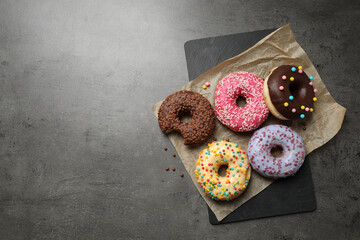 Delicious glazed donuts on grey table, top view. Space for text