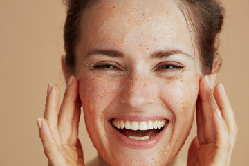 happy modern woman with face scrub against beige background