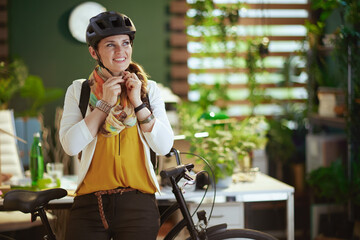 smiling trendy business woman in bike helmet in eco office - obrazy, fototapety, plakaty