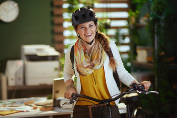 smiling stylish business woman in bike helmet in eco office