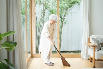 ほうきで部屋の掃除をする日本人女性