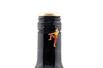 Miniature scene climbing wine bottle to drink