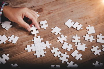 Hands holding jigsaw puzzles piece on wooden table background, success business, solution strategy,...