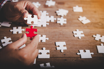 Hands holding jigsaw puzzles piece on wooden table background, success business, solution strategy, teamwork partnership concept