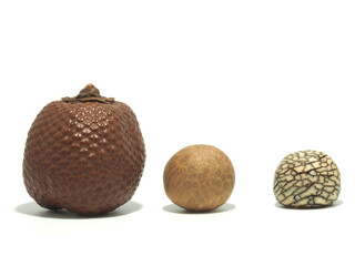 Three laranja nuts also known as buriti fruit (palm seed) in different processing states. In the shell, without the shell and polished. Isolated on a white background.