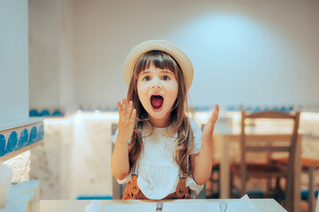 Funny Girl Screaming with Happiness in a Restaurant. Happy little child having a sense of humor and...