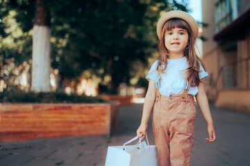 Happy Fashion Toddler Girl Holding a Shopping Bag. Fashionable little child going on a shopping...
