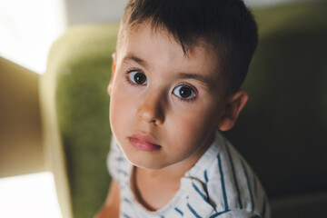 The portrait of a boy looking sadly straight into the camera. Head shot portrait. Little pretty preschooler boy. Lovely kid.