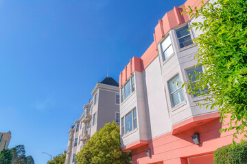 Apartment building with pink and white exterior near an apartment building with emergency stairs