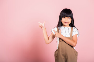 Asian little kid 10 years old point with index finger up at studio shot isolated on pink...