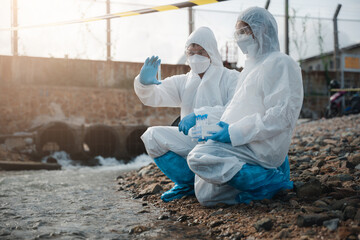 Scientist or Biologist in a protective suit and protect mask collects sample of waste water from industrial for analyze, problem environment, Ecologist sampling water from the river with test tube
