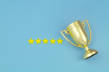 Gold champion trophy cup with five stars on blue background.	