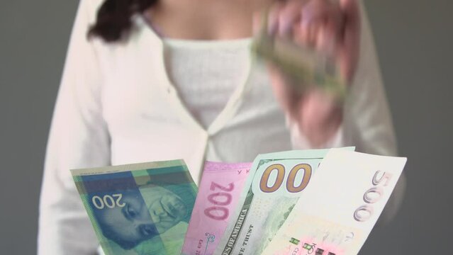 Young woman selec the EORO and reject usd dollar, israel shekel NIS, Ukrainian hryvnia and Czech koruna CZK banknotes. Currency exchange rate concept. Selective focus