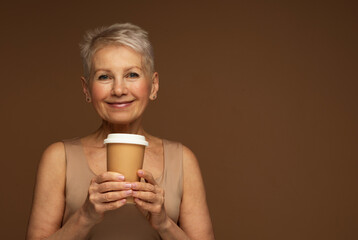 Elderly smiling fashionable woman hold takeaway delivery beige cup coffee to go