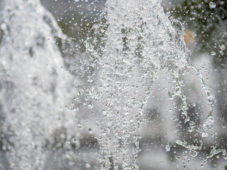 Splashes of water on dark background. Water sprays in sunny day close-up.