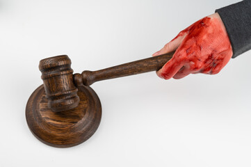 Female judge with bloody hands beats the gavel on a white background.