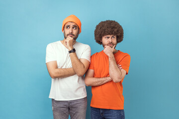 Portrait of two young adult hipster men holding chin with hands, need to think, planning strategy,...