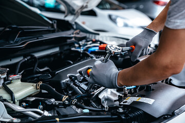 Mechanic using wrench while working on car engine at garage workshop, Car auto services and maintenance check concept. - obrazy, fototapety, plakaty