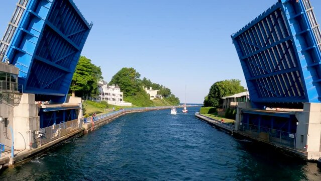 A double-leaf bascule bridge opens wide allow boat traffic through the channel of water. This drawbridge is located on Lake Michigan in the scenic town of Charlevoix, Michigan, USA.