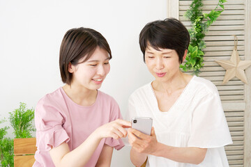 自宅で母親とスマホを使う娘