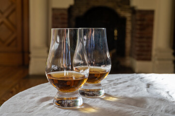 Two glasses of scotch whiskey with view on fireplace in old house on background, Edinburgh whisky tasting tour, Scotland