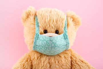 Teddy bear in protective medical mask on a pink background. Pediatrics concept.