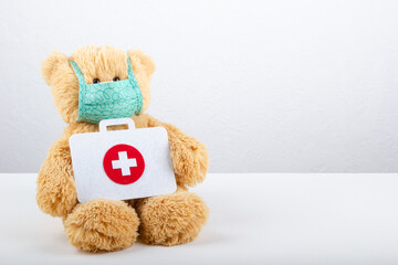 Teddy bear in protective medical mask with a medical kit. Pediatrics concept.