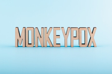 Wooden letters text MONKEYPOX on a blue background. Monkeypox virus concept.