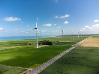 Aerial view on modern wind mills, green grain fields and blue Atlantic ocean in agricultural region...