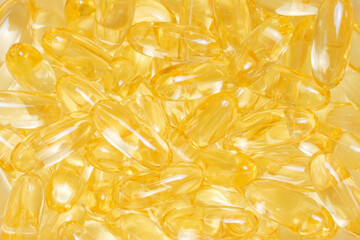 Pile of golden color fish oil capsules close-up top view.