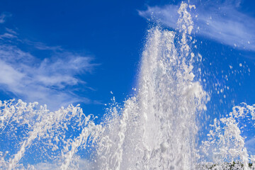 Fanciful shapes formed out of the water chaotically beat up on blue sky background fountain jets up.