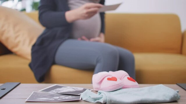 Pregnant woman is preparing clothes for her newborn baby.