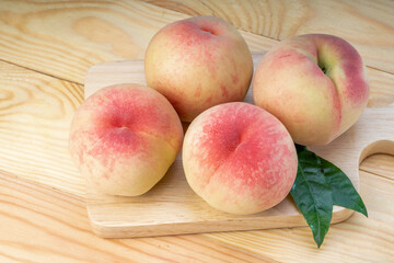 Fresh Sweet Peach on pink wooden  background, Pink and yellow Peach fruit with leaf on Wooden table.