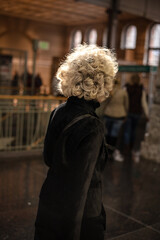 Older woman with grey curls wearing a black coat walking in the city