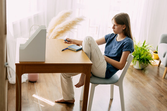 A High School Student Sits At Home At Her Desk, Takes A Break Before Preparing For Classes Or Exams, Studies At Home. The Concept Of Training And Education