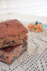 Torta con frutos secos , cuadrados , porciones, dos , frutos secos, nueces, pasas de uva , mantel tejido , pasteleria , hornear, preparar, masa dulce, suave, humedo , sabroso , merienda , desayuno ,